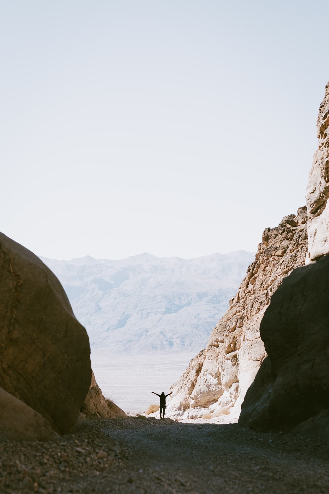 A person standing between canyon walls with mountains in the distance