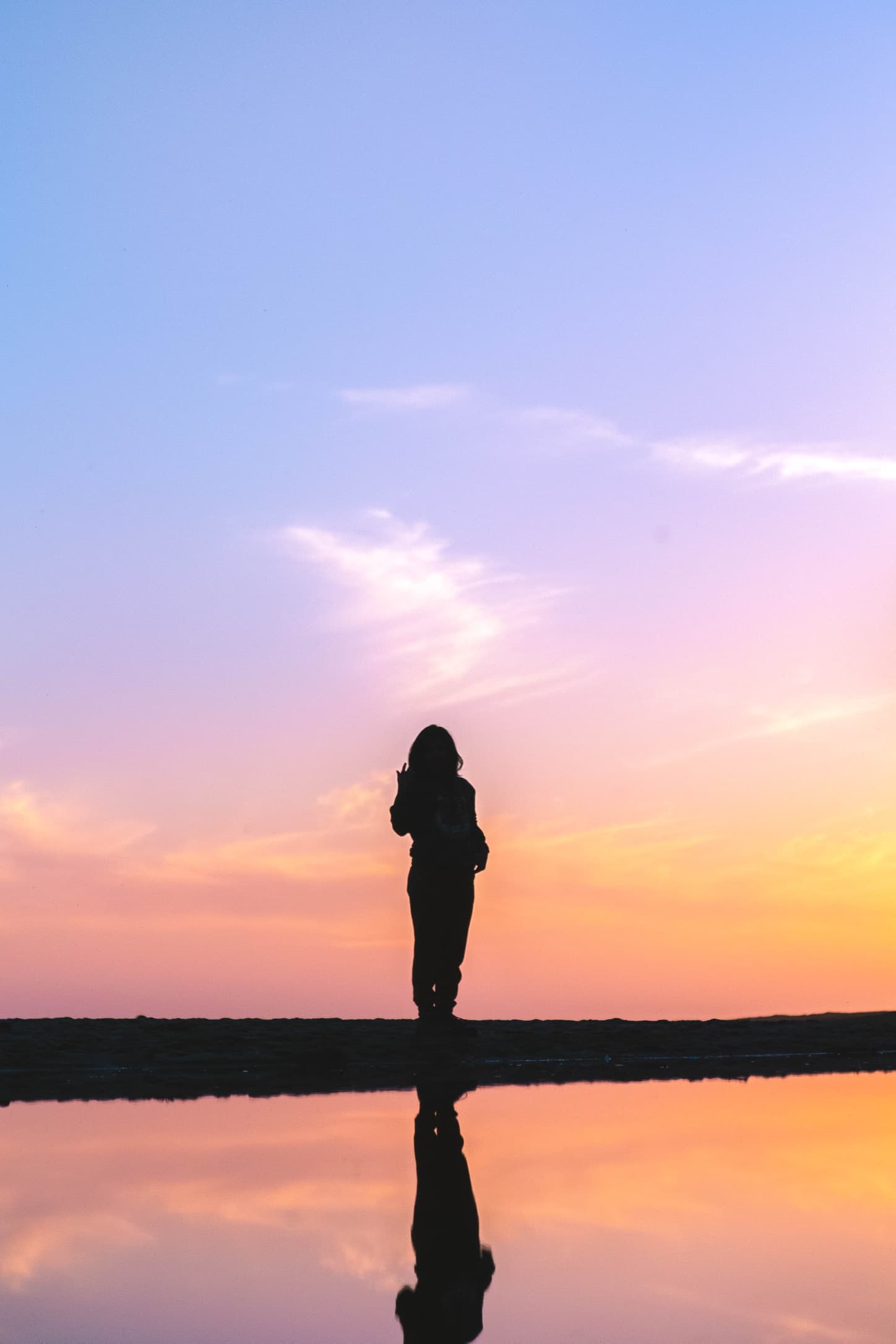 A silhouetted child reflected against a sunset sky