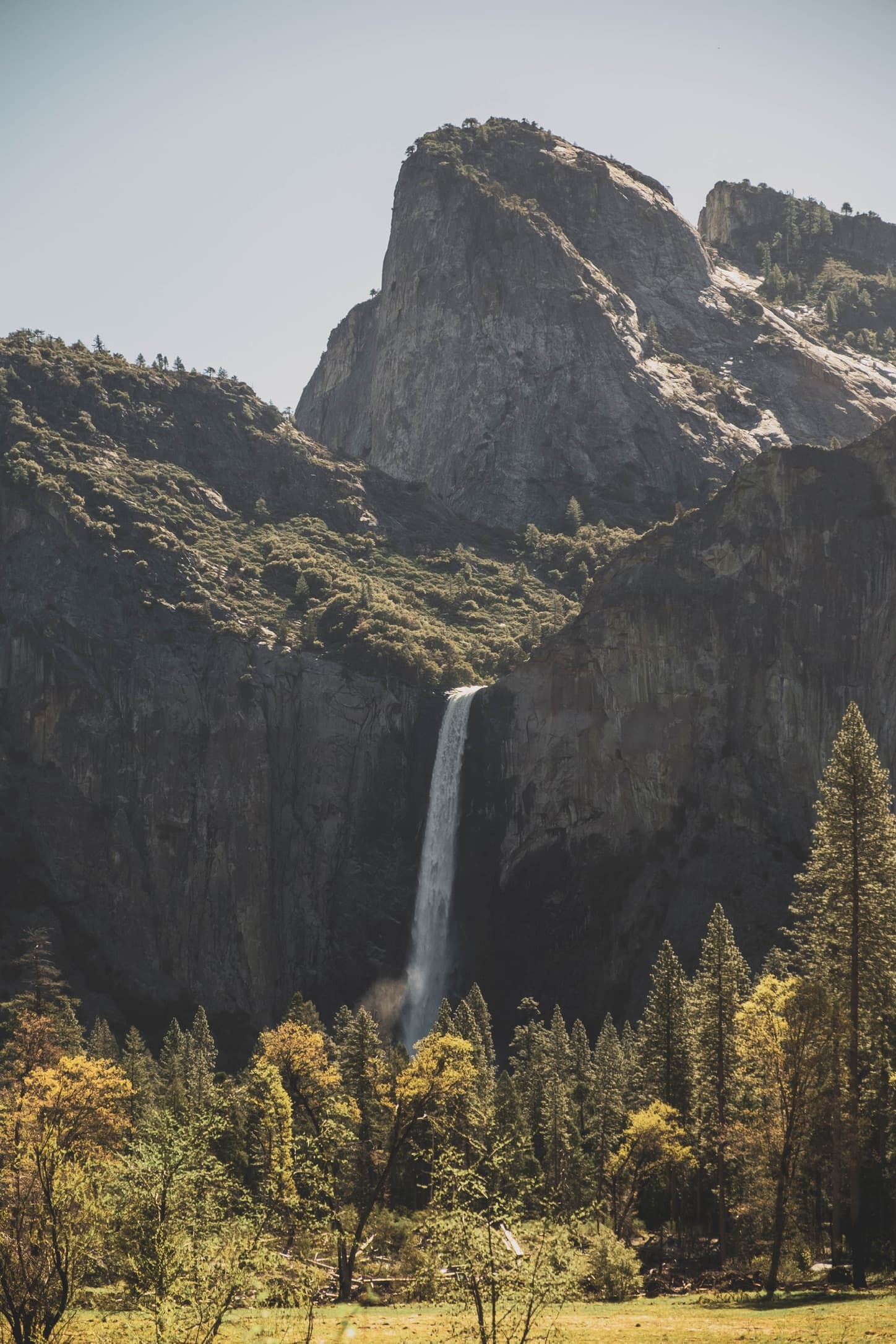 A waterfall dropping between granite cliffs and trees